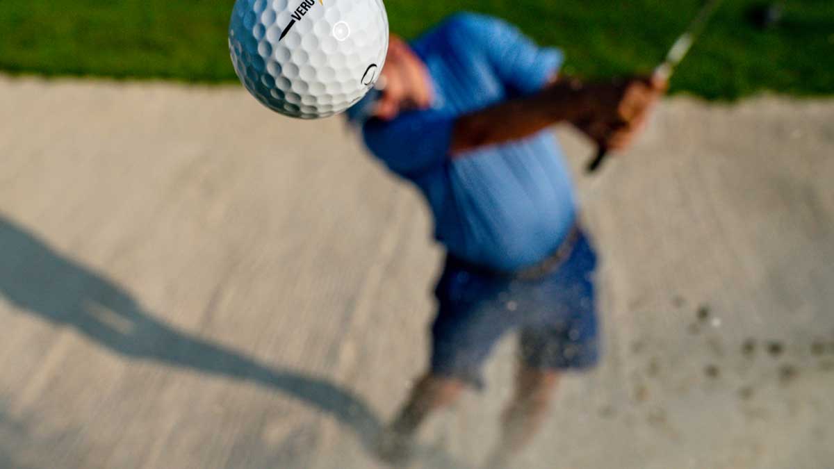 Golfer hitting the ball out of a sand trap.